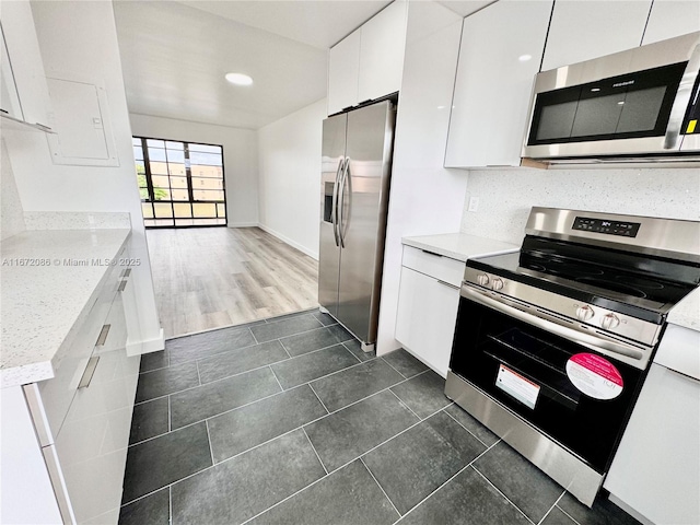 kitchen featuring tasteful backsplash, white cabinetry, appliances with stainless steel finishes, and light stone countertops