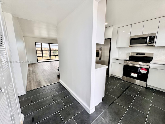 kitchen with stainless steel appliances, white cabinets, and dark tile patterned flooring