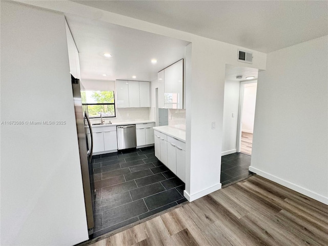 kitchen featuring stainless steel appliances, sink, white cabinets, and decorative backsplash