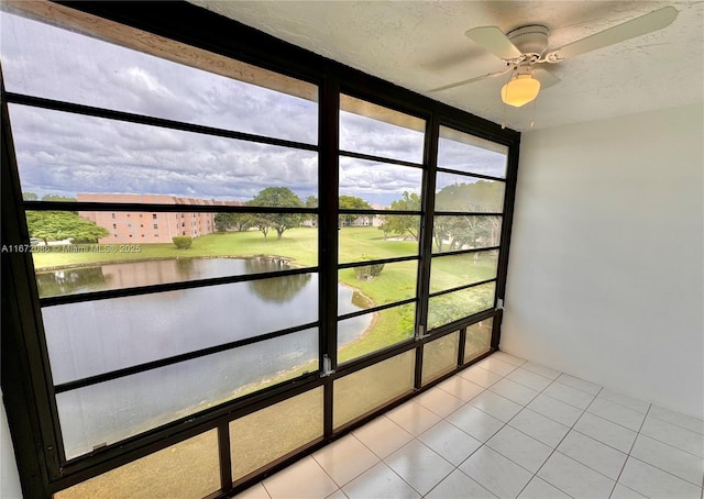 unfurnished sunroom with a wealth of natural light, ceiling fan, and a water view