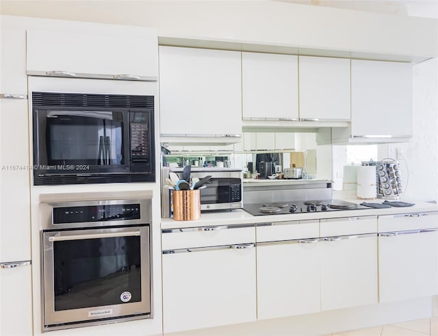 kitchen with light tile patterned flooring, white cabinets, and black appliances