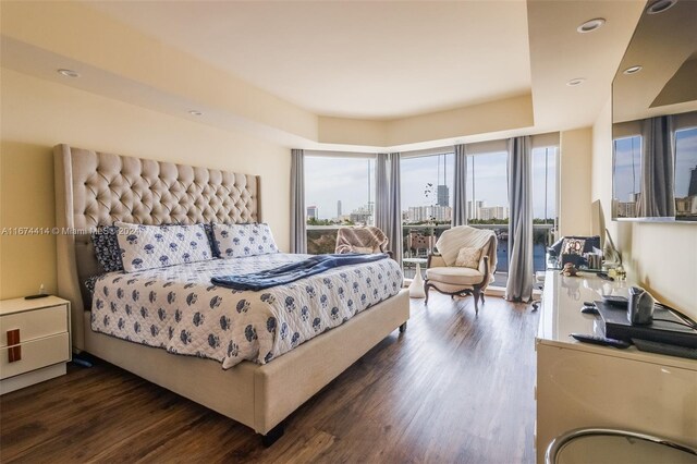 bedroom featuring access to outside, recessed lighting, a view of city, and dark wood-style flooring