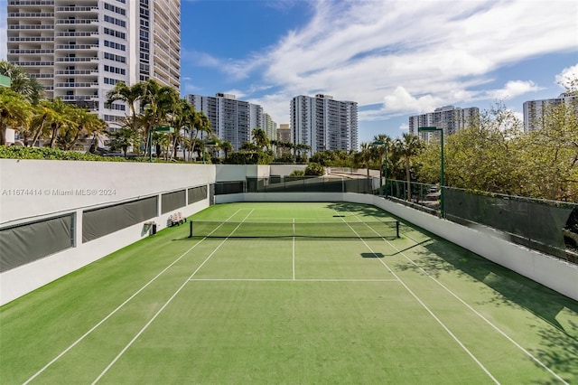 view of tennis court with fence and a view of city