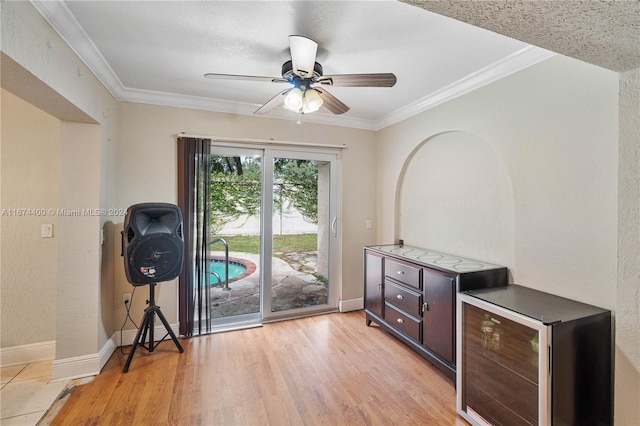 interior space with light hardwood / wood-style floors, wine cooler, ornamental molding, and ceiling fan