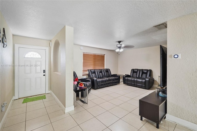 living room featuring light tile patterned flooring, ceiling fan, and a textured ceiling