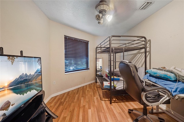 bedroom featuring light hardwood / wood-style flooring and a textured ceiling