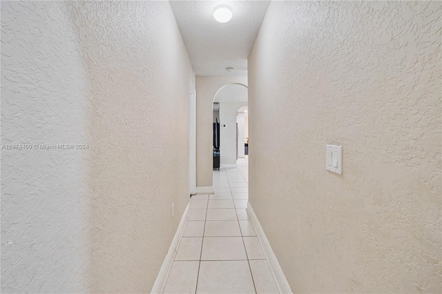 hallway featuring light tile patterned flooring and a textured ceiling