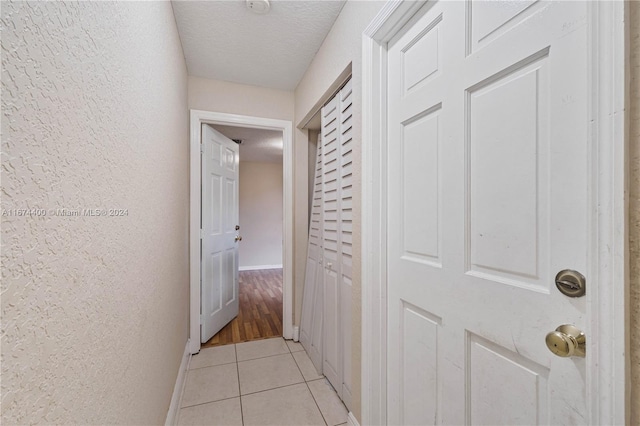 hallway with light hardwood / wood-style floors and a textured ceiling