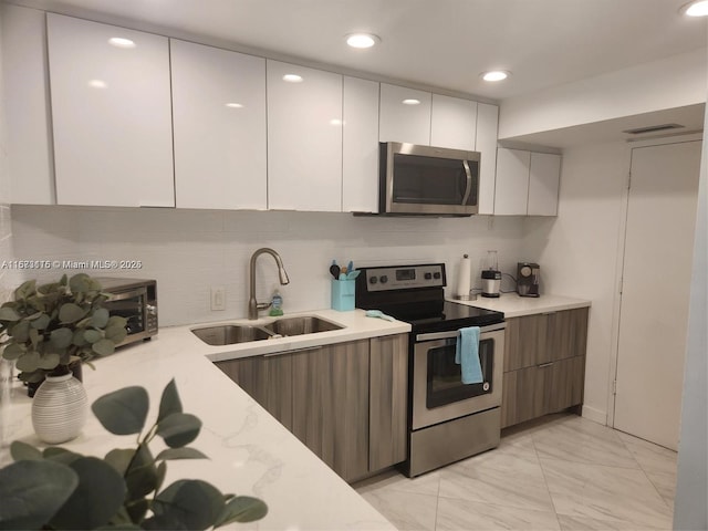 4330 Hillcrest Dr Unit 414, Hollywood, FL 33021 - kitchen featuring appliances with stainless steel finishes, a sink, modern cabinets, decorative backsplash, and light marble finish flooring