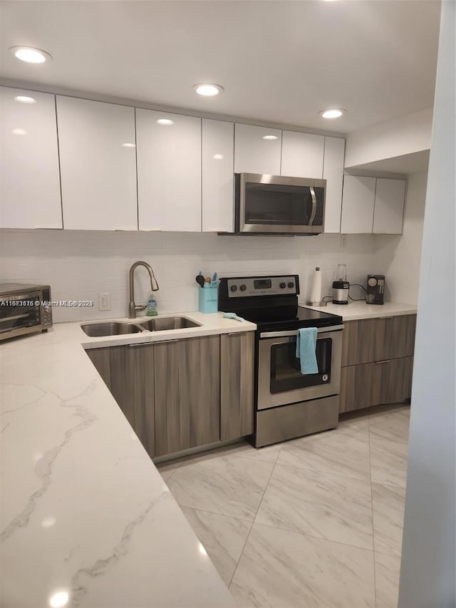 4330 Hillcrest Dr Unit 414, Hollywood, FL 33021 - kitchen featuring appliances with stainless steel finishes, modern cabinets, a sink, light marble finish floors, and recessed lighting