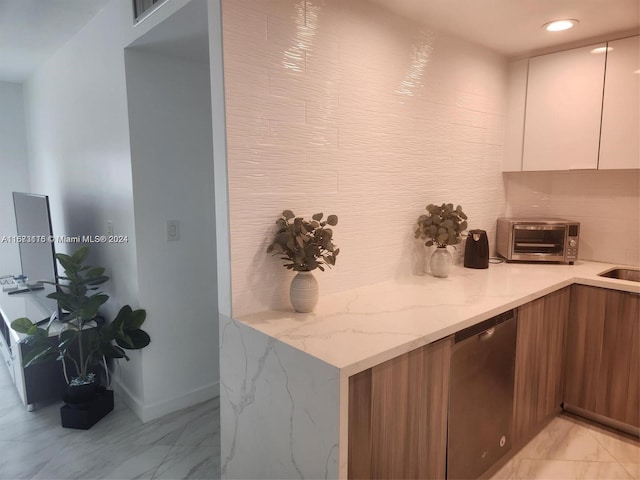 kitchen with dishwasher, light stone countertops, and white cabinetry