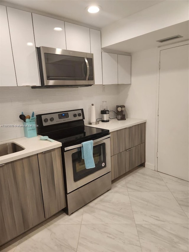 kitchen with tasteful backsplash, appliances with stainless steel finishes, and white cabinetry