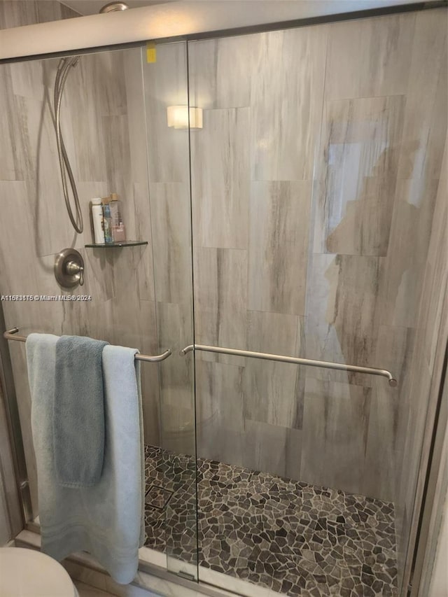 bathroom featuring toilet and a shower with shower door