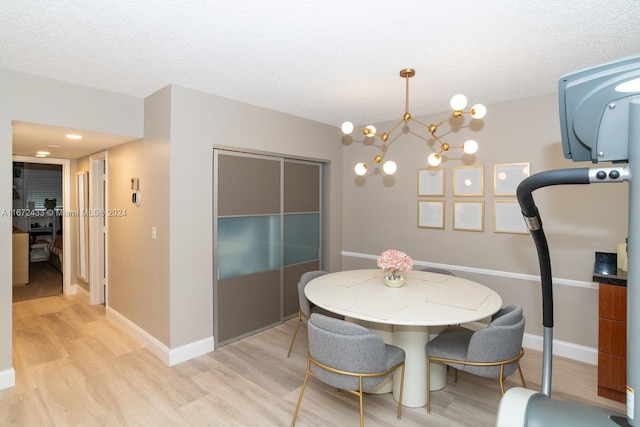 dining space featuring an inviting chandelier, light wood-type flooring, and a textured ceiling