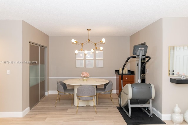 dining space featuring an inviting chandelier, light hardwood / wood-style floors, and a textured ceiling