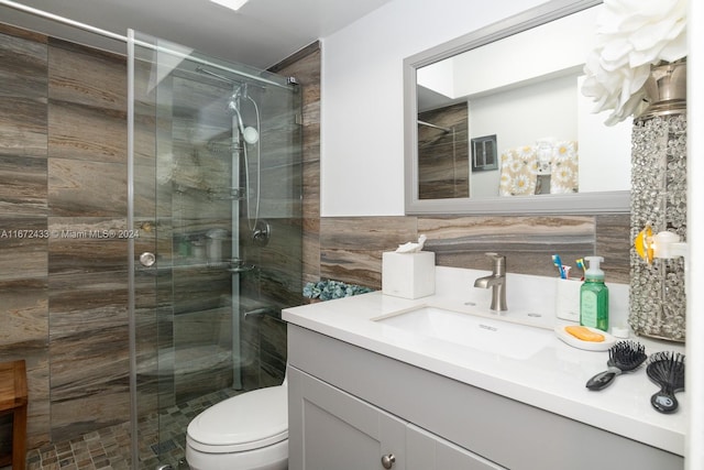 bathroom featuring tile walls, a shower with shower door, vanity, and toilet