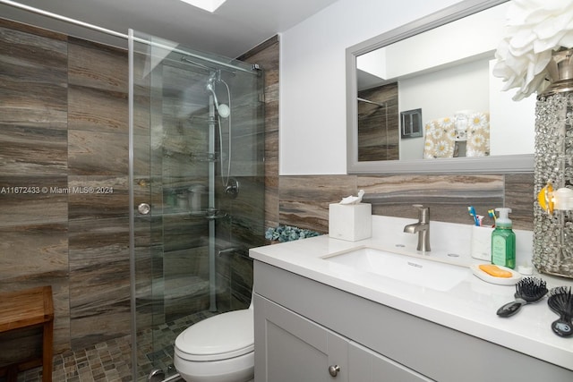 bathroom featuring walk in shower, tile walls, vanity, and toilet