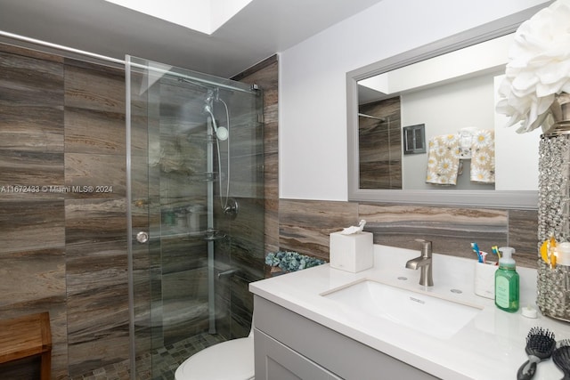 bathroom featuring vanity, a shower with door, and toilet