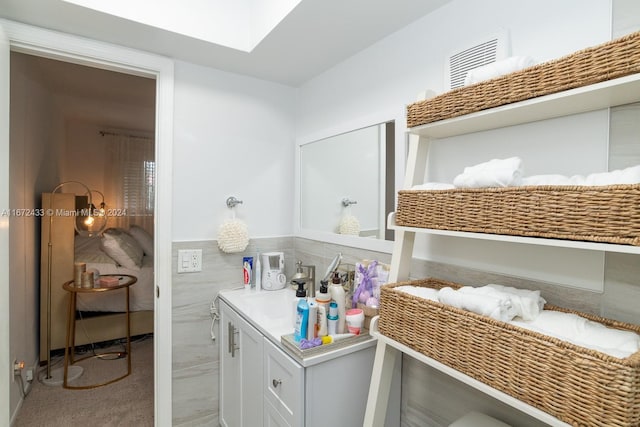 bathroom featuring a skylight, vanity, and tile walls