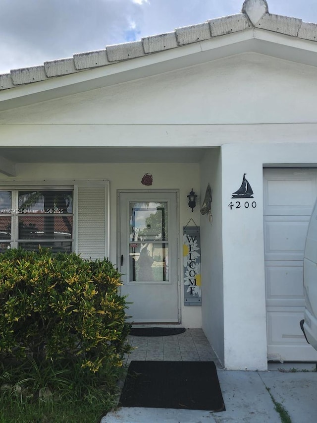 property entrance with stucco siding and a porch