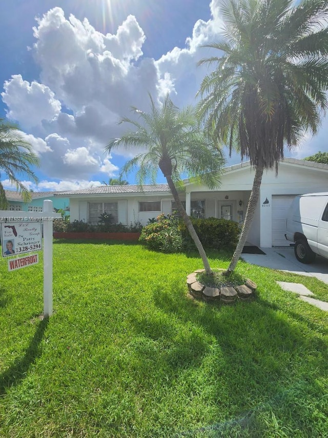 single story home featuring a front lawn and a garage