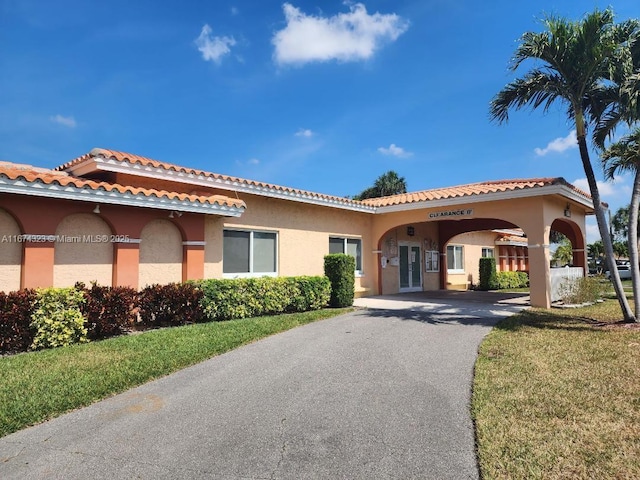 mediterranean / spanish-style house with stucco siding, aphalt driveway, and a tile roof