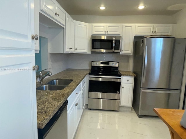 kitchen featuring dark stone countertops, white cabinets, stainless steel appliances, and sink