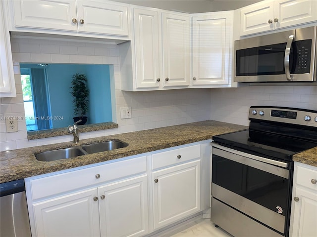 kitchen with dark stone countertops, appliances with stainless steel finishes, sink, and white cabinetry