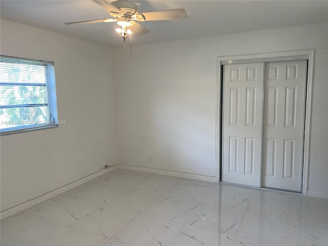 unfurnished bedroom with ceiling fan and a closet