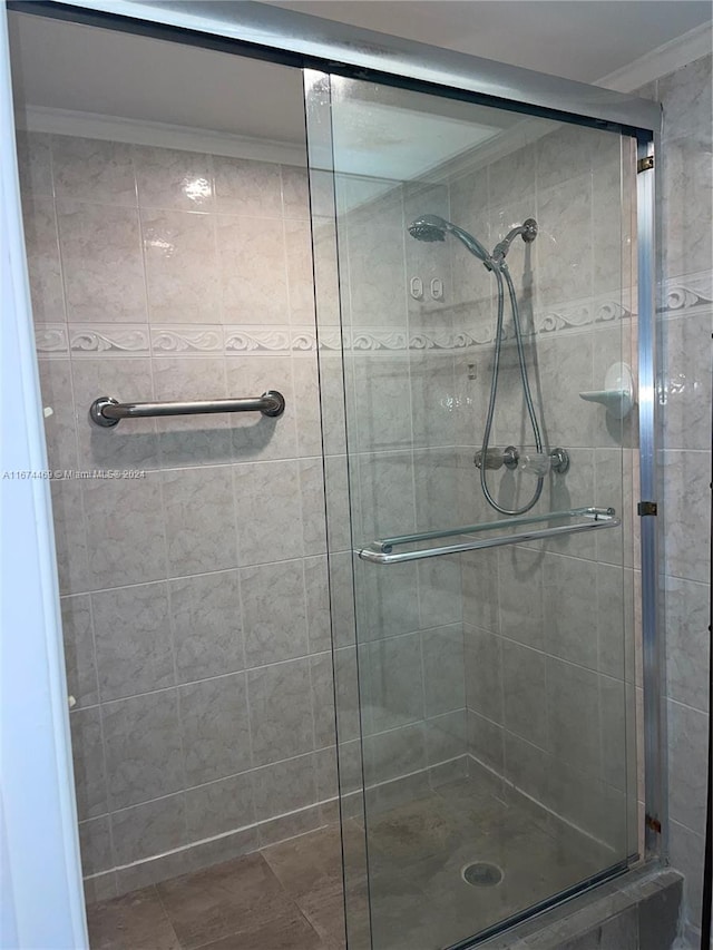 bathroom featuring ornamental molding and a shower with shower door