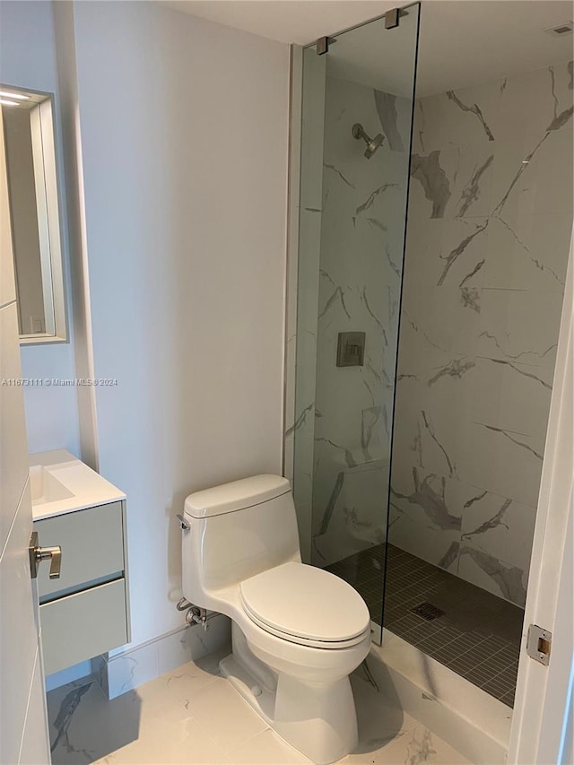 bathroom with a tile shower, vanity, and toilet