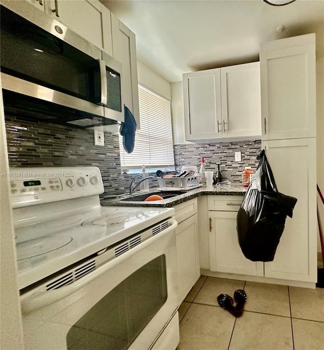 kitchen featuring light tile patterned flooring, white electric stove, tasteful backsplash, and white cabinetry