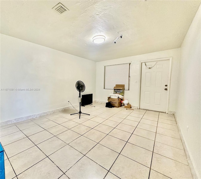 unfurnished room with light tile patterned floors and a textured ceiling