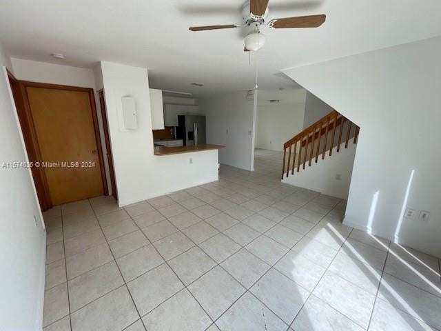 unfurnished living room with light tile patterned floors and ceiling fan