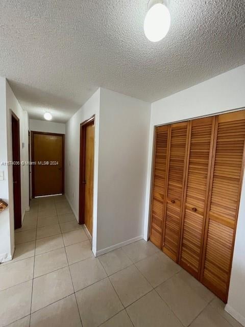 corridor with light tile patterned floors and a textured ceiling