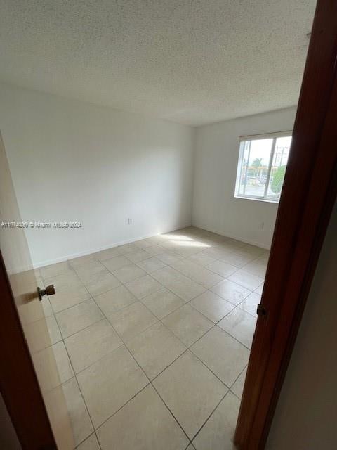 tiled empty room with a textured ceiling