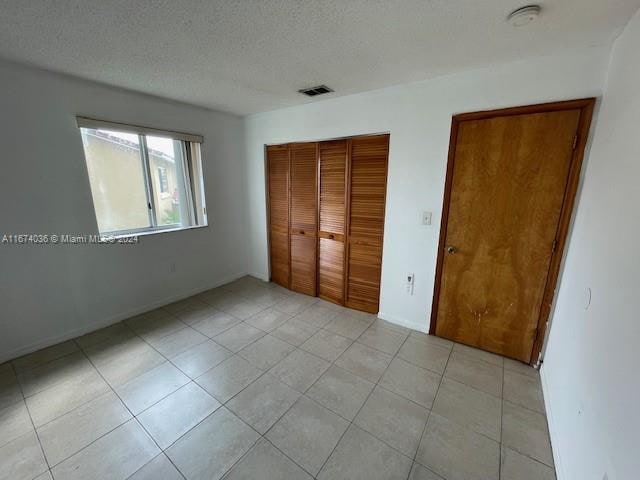 unfurnished bedroom with light tile patterned flooring, a closet, and a textured ceiling