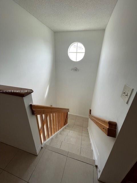 stairway featuring tile patterned flooring and a textured ceiling