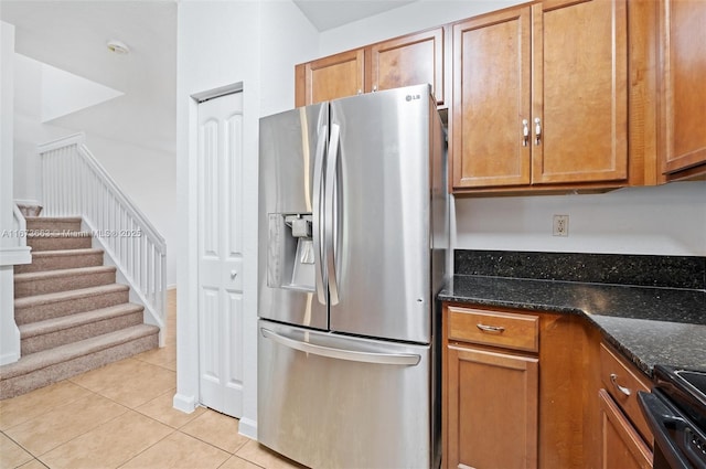 kitchen featuring sink, light tile patterned floors, dark stone countertops, stainless steel appliances, and a textured ceiling