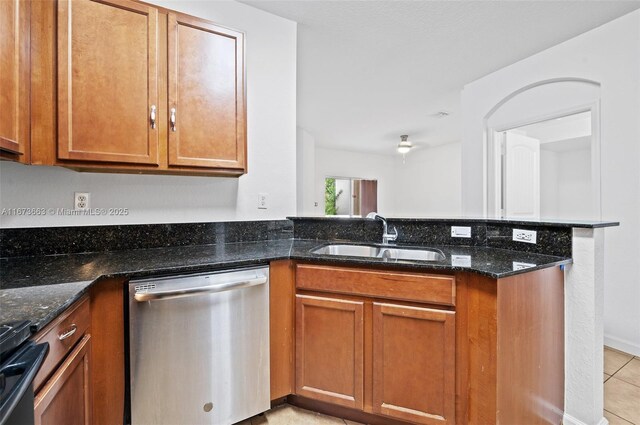 kitchen featuring stainless steel refrigerator with ice dispenser, stove, light tile patterned flooring, and dark stone counters