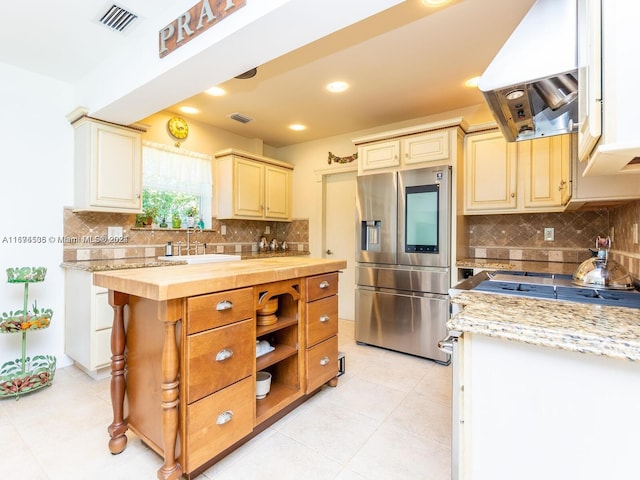 kitchen featuring tasteful backsplash, island exhaust hood, sink, butcher block counters, and stainless steel refrigerator with ice dispenser