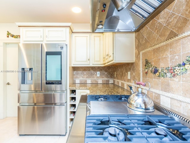 kitchen featuring extractor fan, cream cabinets, tasteful backsplash, light stone countertops, and stainless steel fridge with ice dispenser