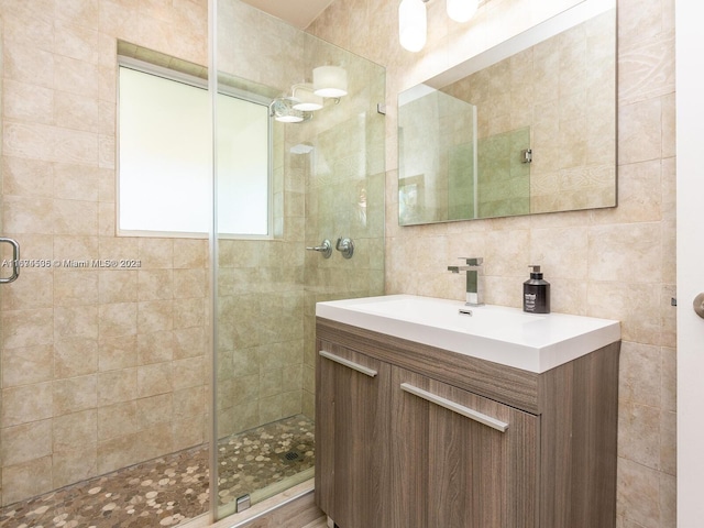 bathroom with vanity, tile walls, a shower with shower door, and decorative backsplash