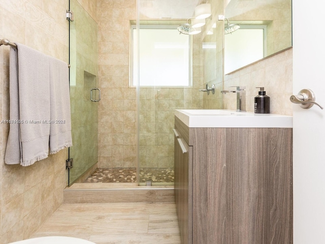 bathroom featuring an enclosed shower, tile walls, and vanity