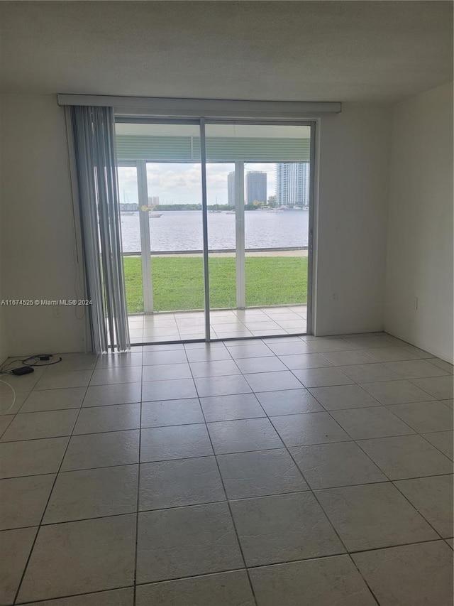 tiled empty room with a water view and a wealth of natural light