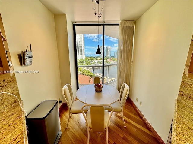 dining space with expansive windows, baseboards, and wood finished floors