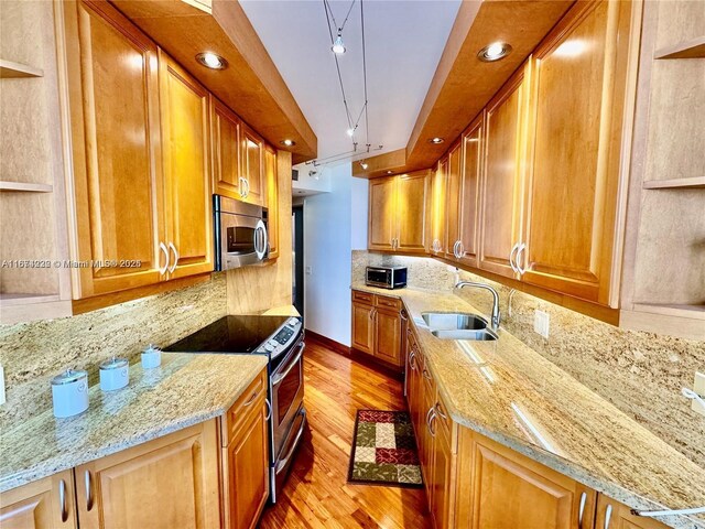 kitchen featuring appliances with stainless steel finishes, light hardwood / wood-style flooring, sink, and light stone counters