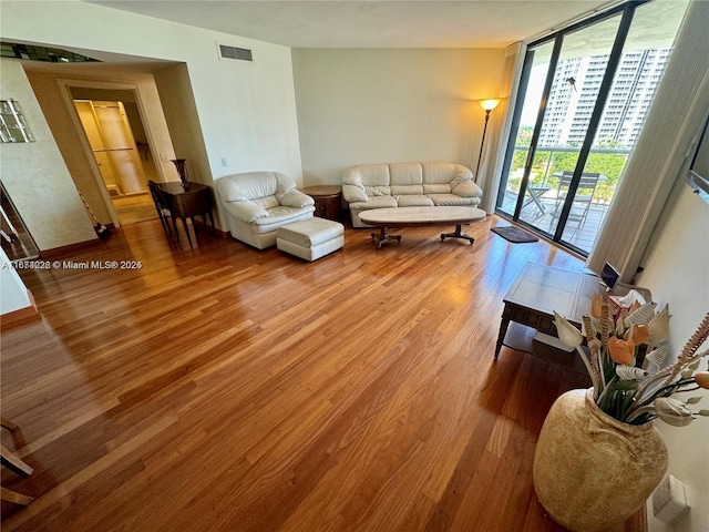 living area featuring a wall of windows, visible vents, and wood finished floors