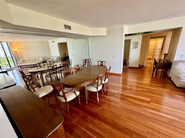 dining area featuring a barn door, visible vents, baseboards, and wood finished floors