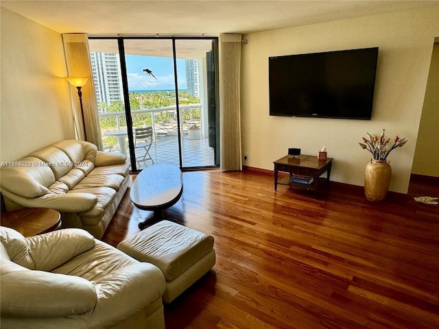 living area with a wall of windows, wood finished floors, and baseboards